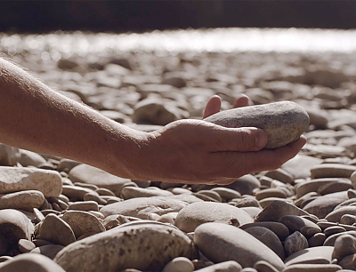 Filmcover: Eine Hand hält einen Stein