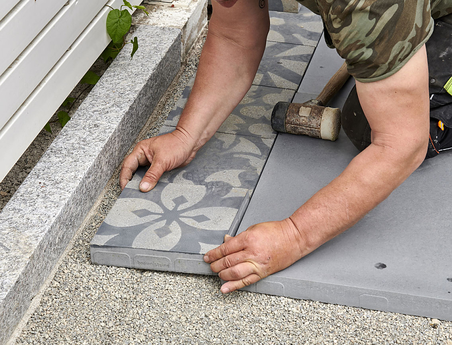 Ein Arbeiter verlegt CEMENTO Terrassenplatten.