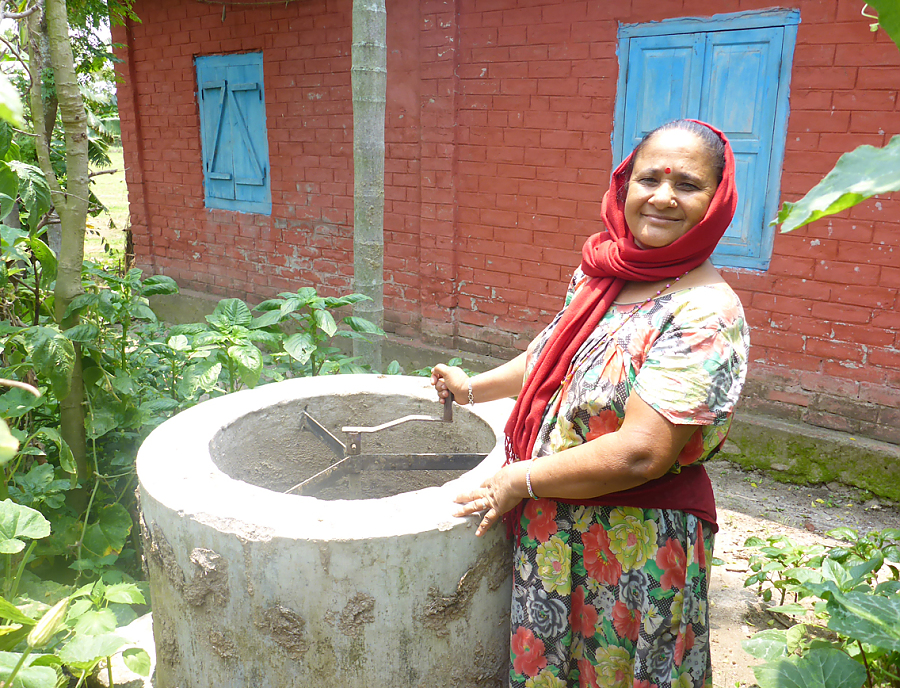 Eine nepalesische Frau befüllt eine Kleinbiogasanlage.