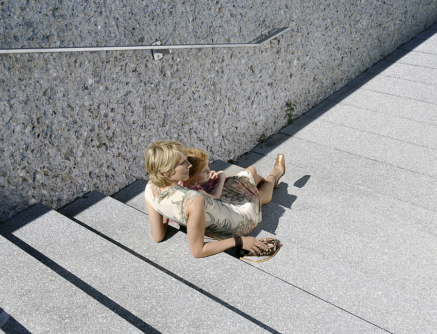 ARCADO Stufen aus Beton in der Farbe Opalgrau. Darauf liegend eine Frau mit einem Kind.