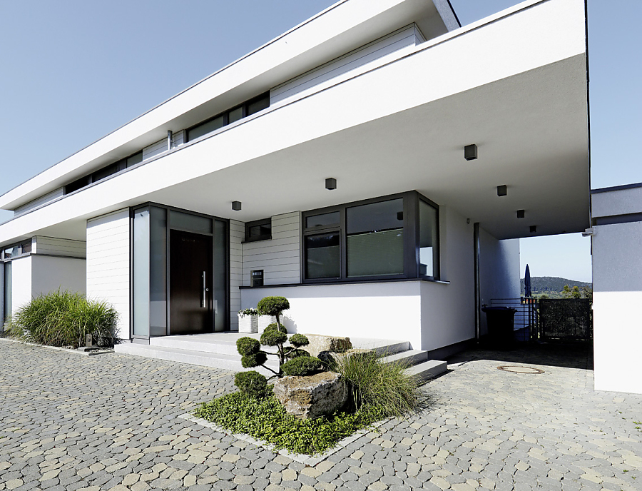 ARENA Pflastersteine aus Beton in der Farbe Staufer-Schattiert im Hof eines modernen Hauses in weiß.
