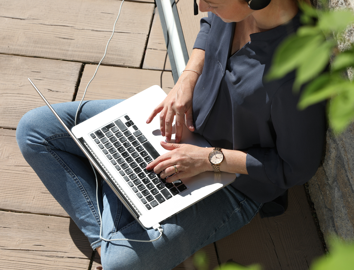 Eine Frau sitzt auf dem Boden mit einem Laptop auf dem Schoß