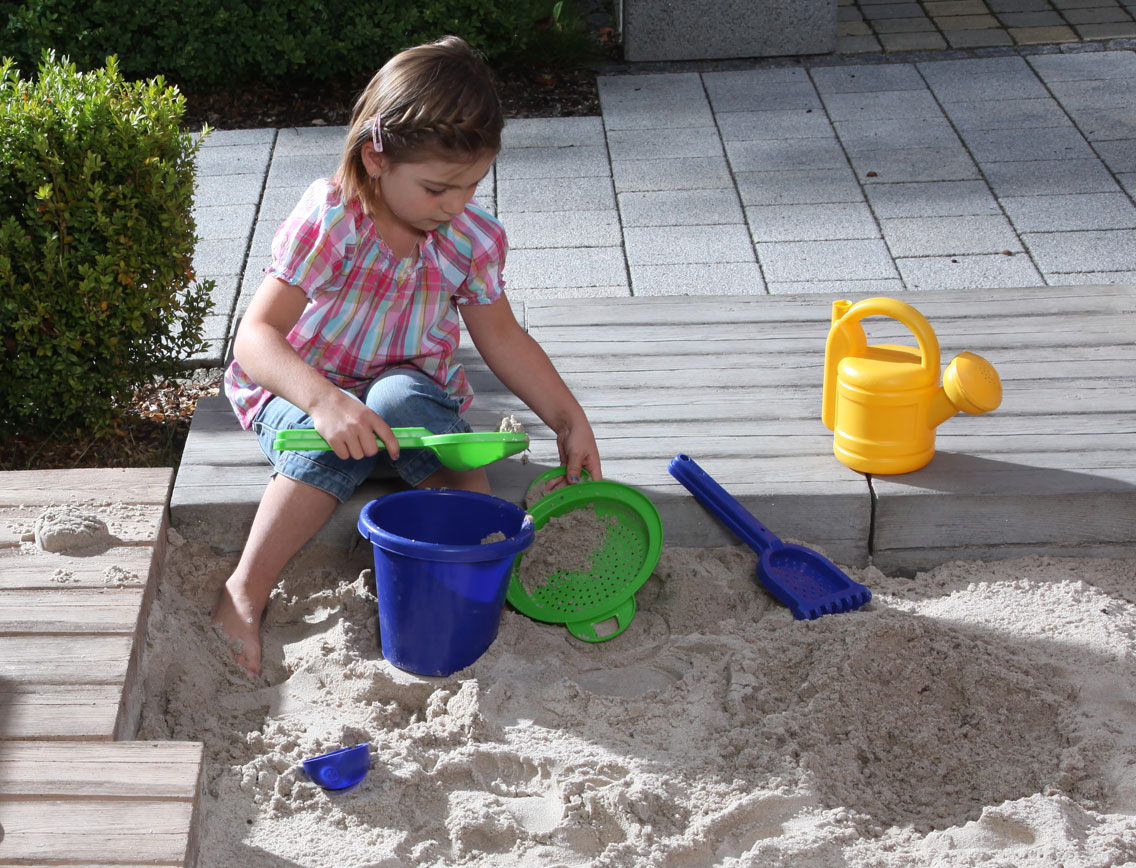 Ein Mädchen spielt in einem Sandkasten
