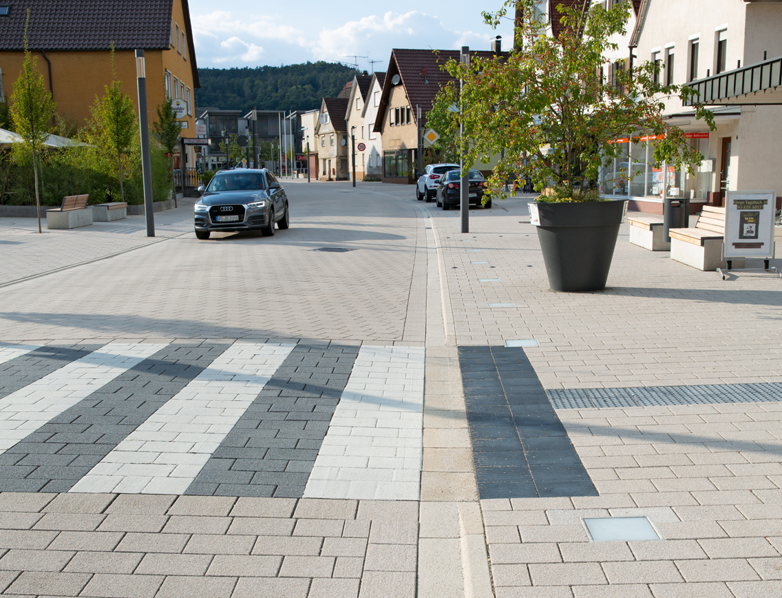 Ortsdurchfahrt mit Zebrastreifen und Bodenindikatoren.